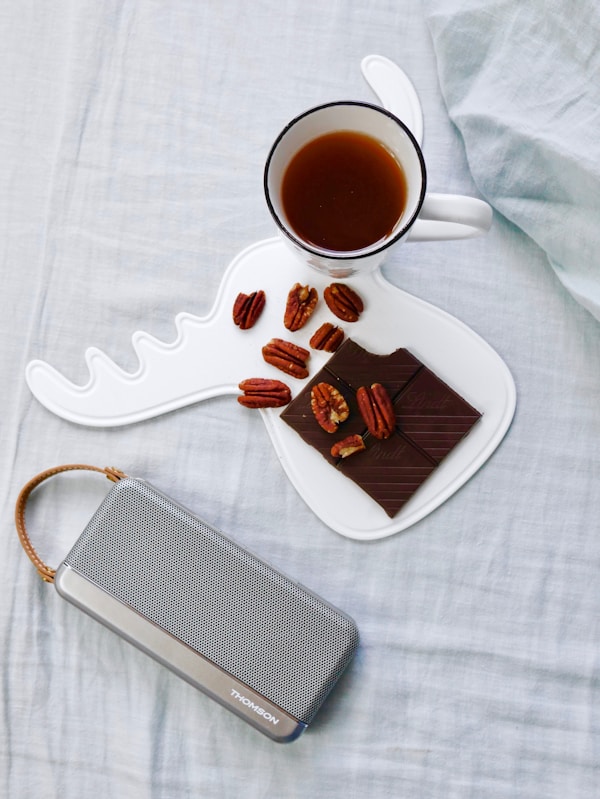 Walnuts on white tray beside cup of coffee