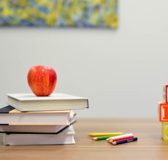 red apple fruit on four pyle books