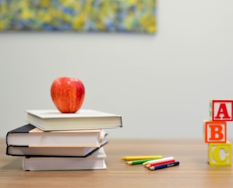 red apple fruit on four pyle books