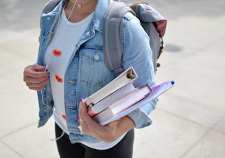 woman wearing blue denim jacket holding book