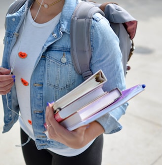 woman wearing blue denim jacket holding book