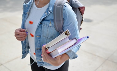 woman wearing blue denim jacket holding book