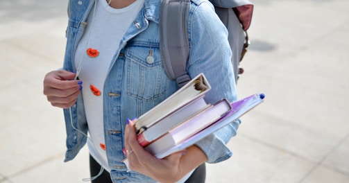 woman wearing blue denim jacket holding book