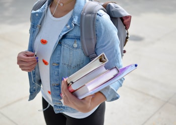 woman wearing blue denim jacket holding book