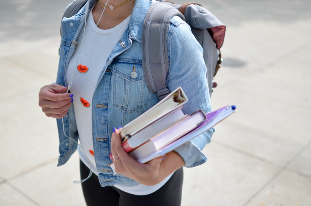 donna che indossa giacca di jeans blu che tiene il libro