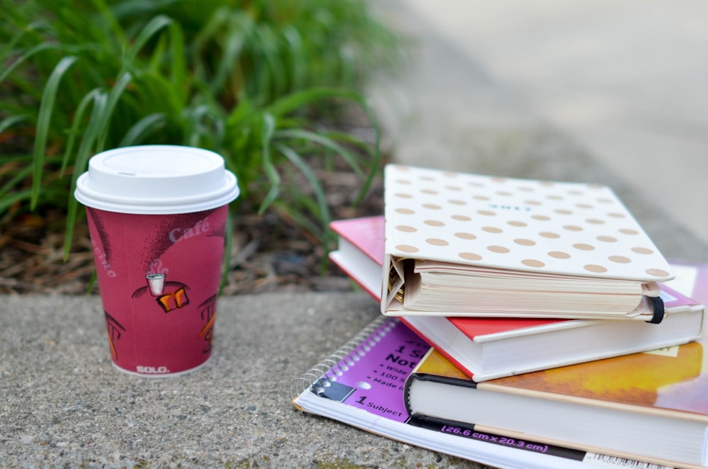 red and white cup beside book