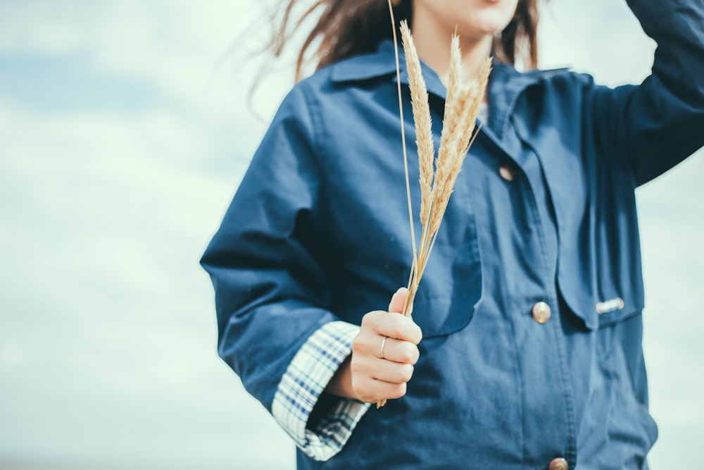 closeup photo of woman wearing blue top holding wheat