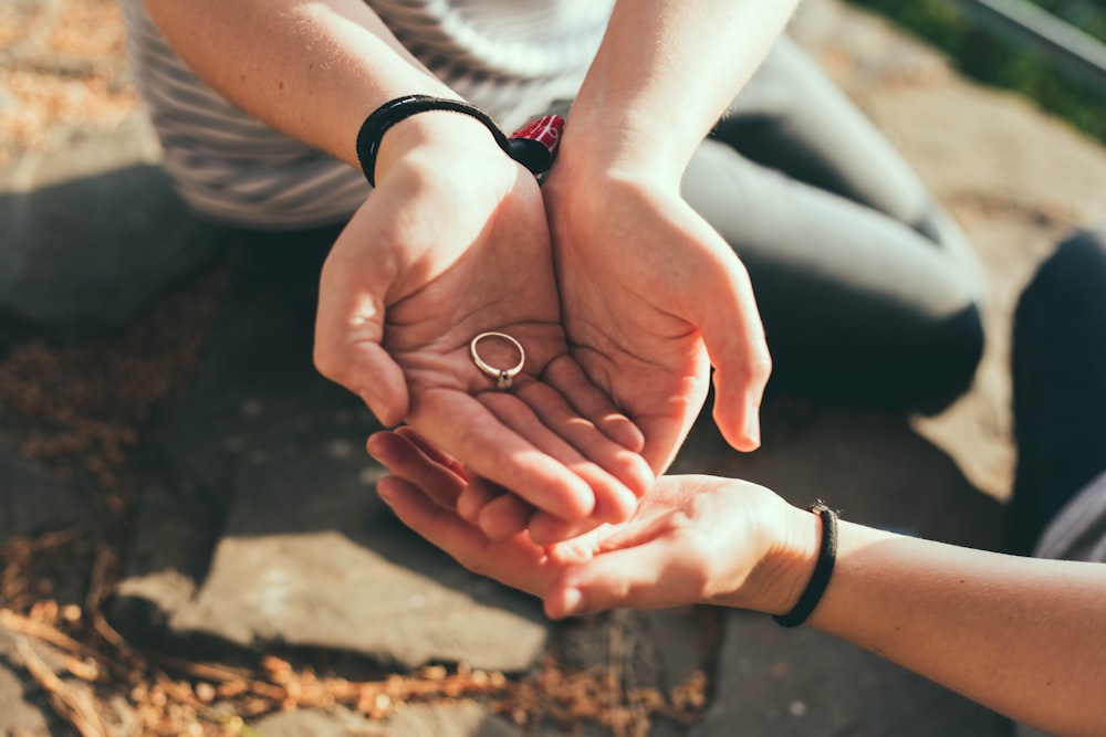 person giving ring to another hand during daytime