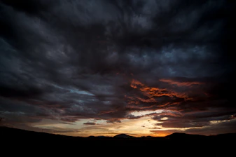 silhouette of mountains under cloudy sky