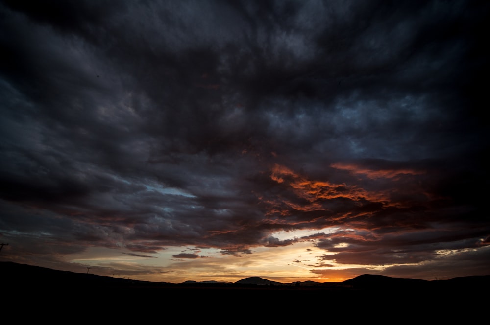 silhouette of mountains under cloudy sky