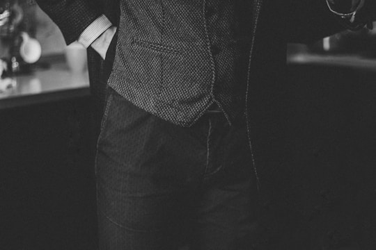 A sleek black and white photo of a finely tailored men's suit with subtle golden accents on the buttons and stitching.