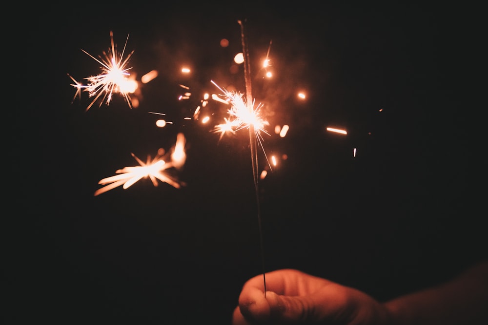 person holding sparkler during nighttime