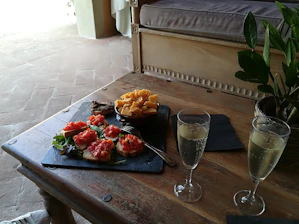 A rustic wooden table set with a plate of bruschetta topped with fresh tomatoes and basil, bathed in natural light.