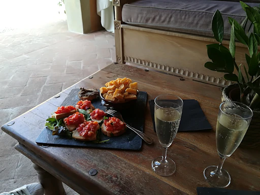 A rustic wooden table set with a plate of bruschetta topped with fresh tomatoes and basil, bathed in natural light.