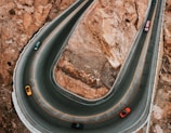 A scenic view of a winding road with cars driving enthusiastically.