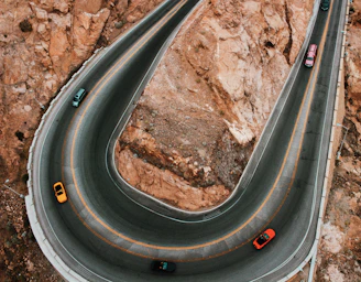 An aerial shot of a twisty mountain road with multiple motorcycles in formation.