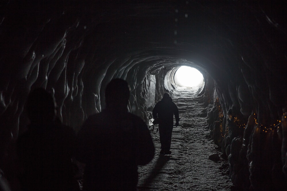 silhouette de trois personnes marchant à l’intérieur du tunnel