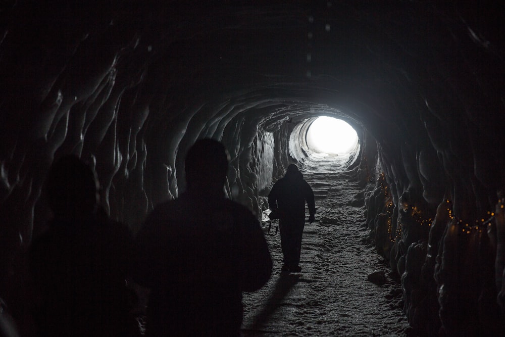 Silhouette von drei Personen, die in den Tunnel gehen