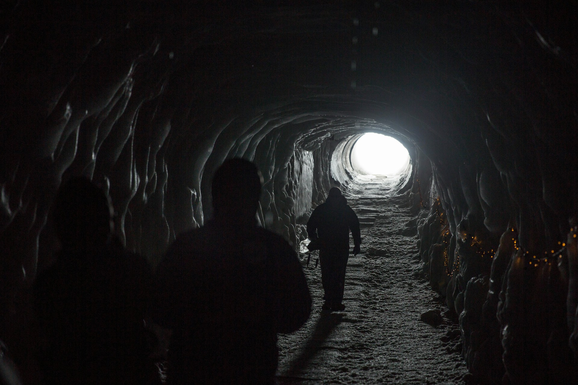 silhouette of three person walking inside tunnel