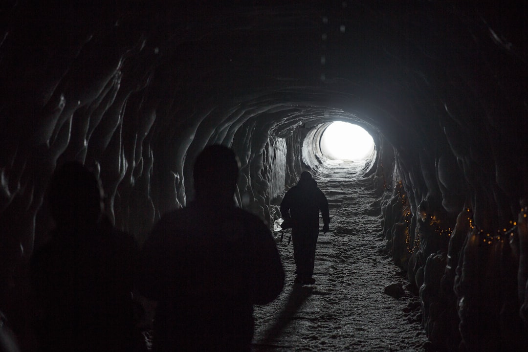 silhouette of three person walking inside tunnel