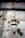 A weathered and deteriorating industrial wall features peeling paint, rust spots, and exposed metal rods. There is a black cable running vertically across the surface, and visible patches of mold or mildew contribute a sense of decay.