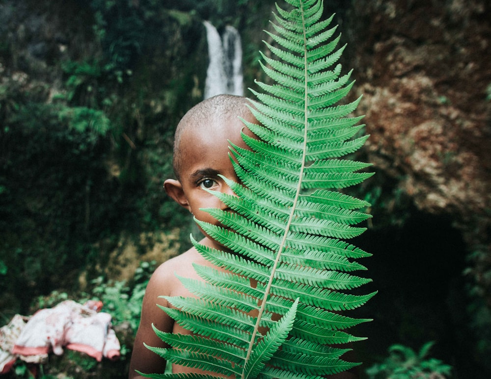 boy standing in behind plant