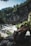 Close-up of a waterproof backpack resting on wet rocks by a mountain stream.
