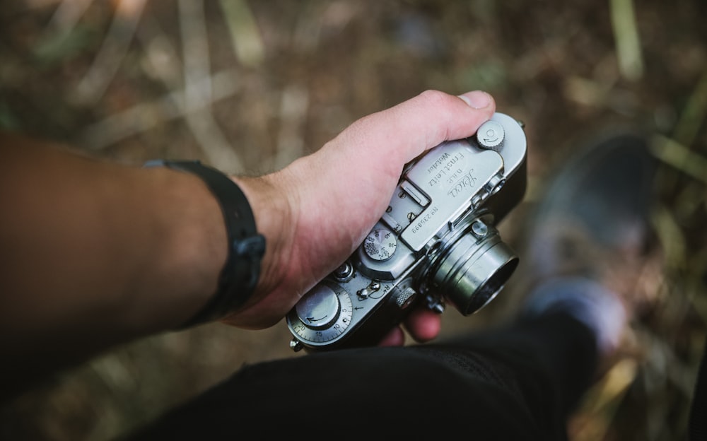 person holding silver point-and-shoot camera