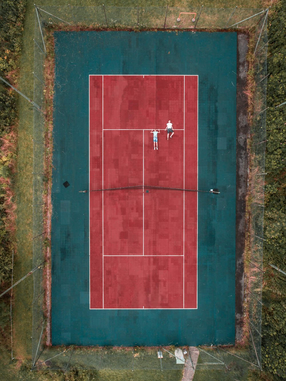 two person lying on tennis court