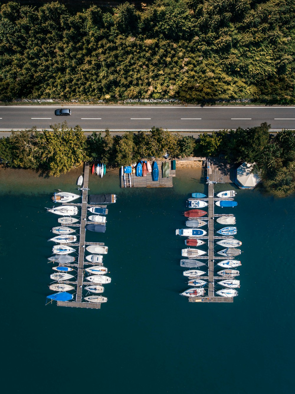 Foto aérea de docas de madeira marrom ao lado da estrada com barcos de cores variadas estacionam nas docas durante o dia