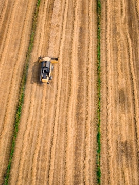 aerial photography of yellow cultivator on brown field