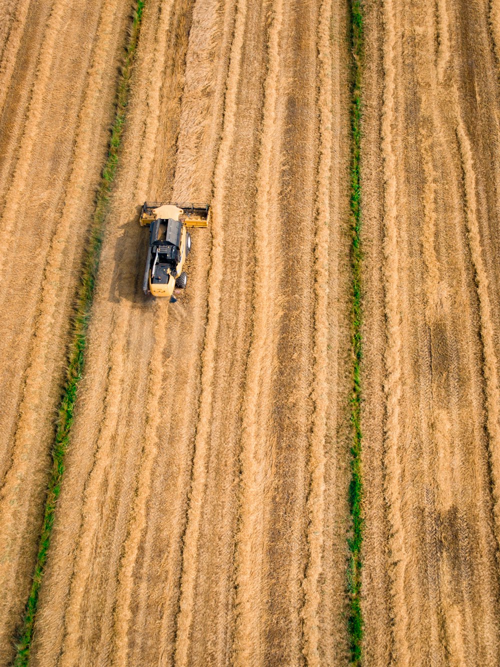 Photographie aérienne d’un cultivateur jaune sur une friche industrielle