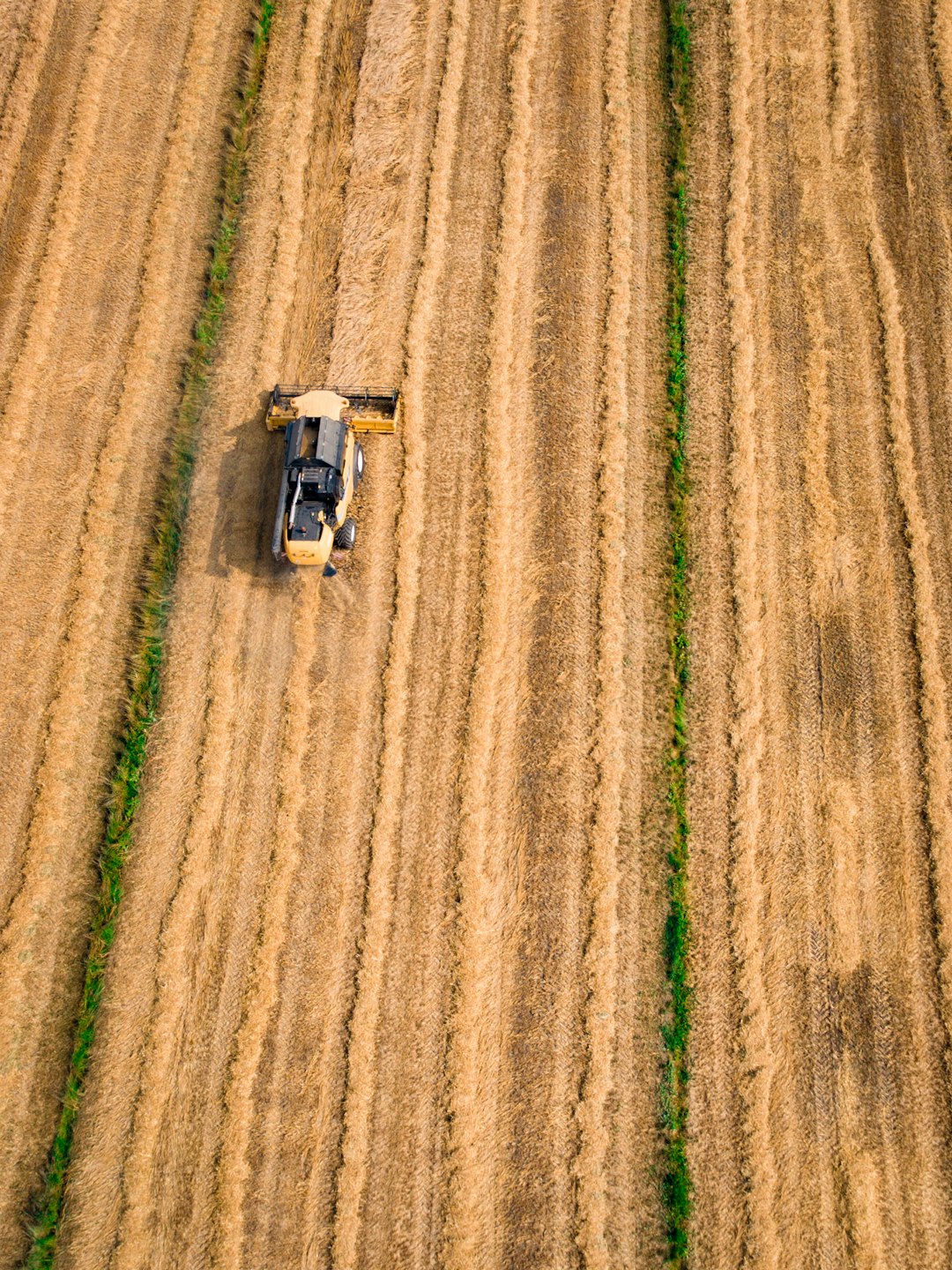 aerial photography of yellow cultivator on brown field