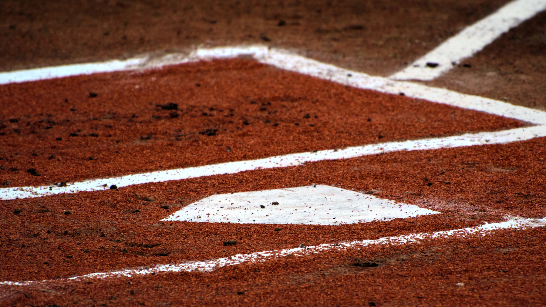 Home plate and the chalked batter's boxes on red infield dirt
