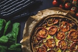 A rustic French tart topped with colorful seasonal vegetables, glowing in natural light.