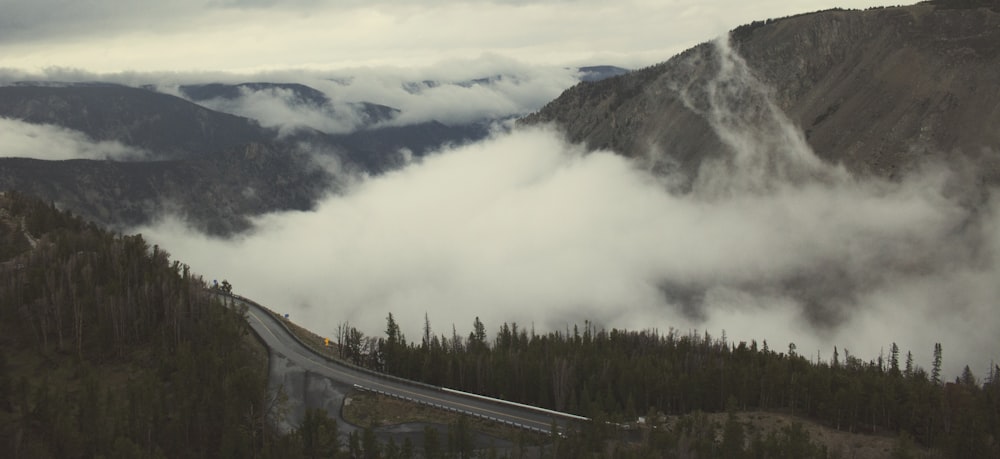 aerial photo of road and mountains with white fogs at daytime