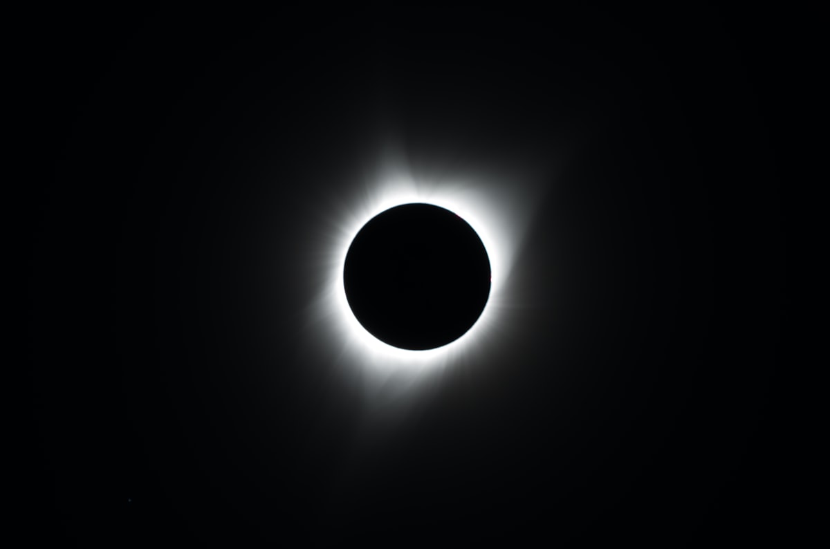 Total solar eclipse with the sun's corona visible around a dark moon.