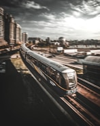 Photo of a modern high-speed train gliding on tracks through a cityscape at dusk