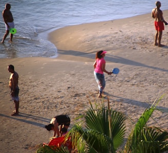 A joyful family playing on a sunny beach with palm trees.