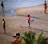 A family enjoying a sunny beach day with children playing in the sand.