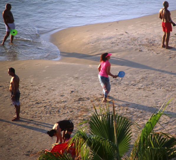 A joyful family playing on a sunny beach with palm trees.