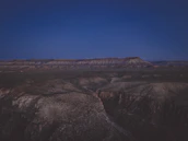 A panoramic view of a sprawling desert mega-project site under a deep navy sky with illuminated infrastructure.