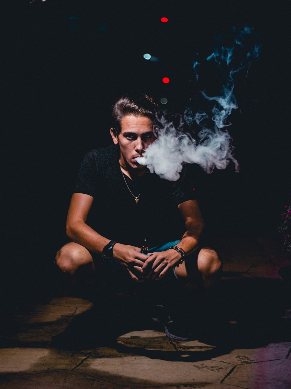 person smoking while squatting during night time