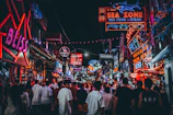 City street at night illuminated by colorful neon signs and bustling crowds.