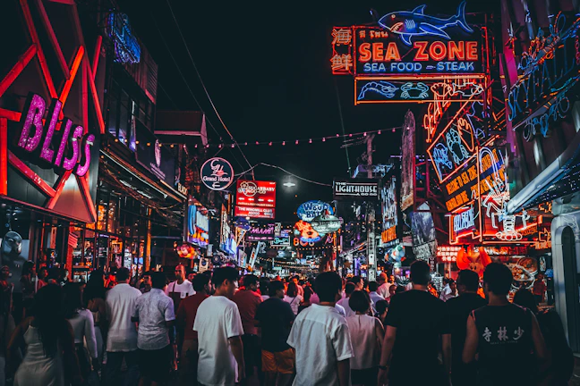 A vibrant neon-lit street scene buzzing with nightlife energy.