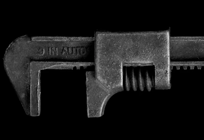 Close-up of a 3D printed wrench resting on a car engine block, showcasing fine detail and durability.