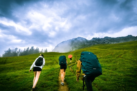 four person hiking on mountain hill during daytime
