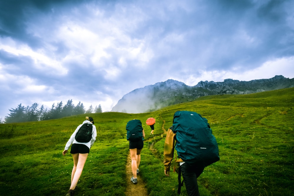 four person hiking on mountain hill during daytime