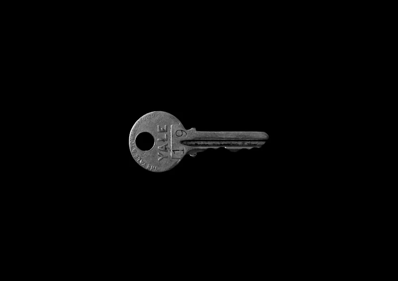 A single silver cylinder key on a plain black background