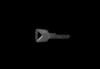 A single metallic key on a black background, featuring a rectangular head with textured grooves and a triangular cutout.